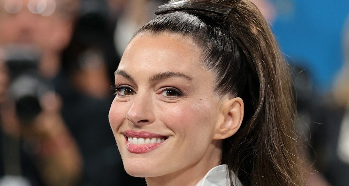 Anne Hathaway prend une chute dans des talons cloutés et une chemise tartan transparente