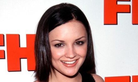 Icône de film des années 90 Wows dans une robe bustier perlée pendant une apparence rare sur le tapis rouge avec son fils