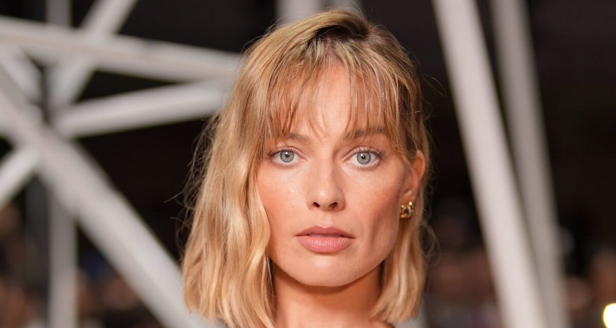 Margot Robbie arrive à PFW dans un haut transparent et un carré blond fraîchement coupé